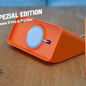 Könnte beinhalten: Orangene Ladestation für iPhone 17 Pro & Pro Max mit weißem Ladepad. Der Text "SPEZIAL EDITION" und "iPhone 17 Pro & Pro Max" sind sichtbar. Ein oranges iPhone 17 Pro Max ist ebenfalls im Bild.