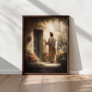 May include: A framed print depicts a figure in a cream-colored robe standing at a wooden door. The artwork features a warm color palette with flowers and greenery surrounding the entrance. The frame is a dark brown color.