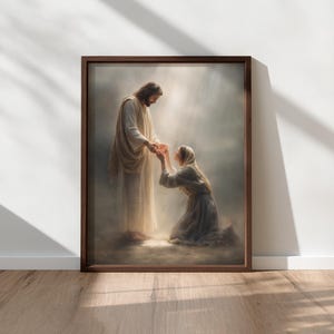 May include: A framed print depicts a religious scene. A figure in a white robe extends a hand to a kneeling person in a long dress. The artwork is set against a backdrop of soft light and a brown wooden frame.