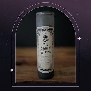 May include: A dark gray glass candle with a label that reads "Lady Luna's The Siren's Whisper." The label features a mermaid illustration and text that says "Awaken the power of attraction through your beauty and confidence."