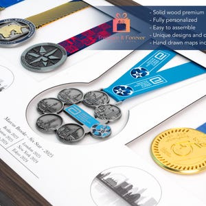Pu&ograve; includere: Un'esposizione incorniciata di medaglie di maratona, con vari disegni e colori. La cornice include medaglie con nastri blu, rossi e dorati. Il testo sul display include "Marcus Brooke - Six Star - 2025" e le citt&agrave; Berlino, Boston, Chicago, Londra, New York e Tokyo.