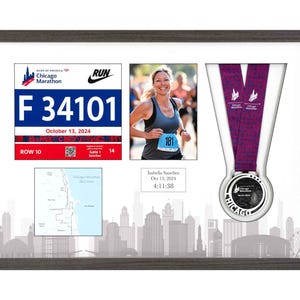 May include: Framed Chicago Marathon memorabilia. Includes a race bib with "F 34101" and "October 13, 2024", a photo of a runner, a map, and a finisher's medal. The frame has a cityscape silhouette at the bottom.