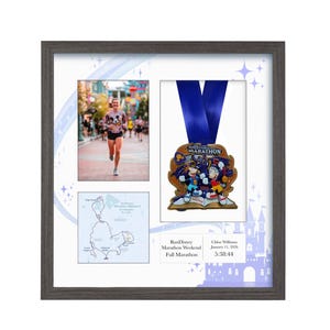 May include: Framed RunDisney Marathon Weekend memorabilia. The frame contains a photo of a runner, a map, and a medal with a blue ribbon. The medal features cartoon characters. The frame is gray.