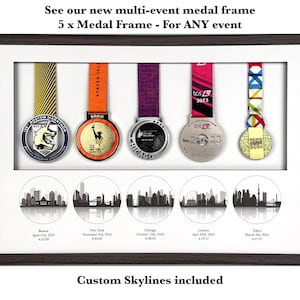 Puede incluir: Un marco rectangular de madera oscura que contiene cinco medallas de marat&oacute;n colgantes con cintas de colores. Debajo de las medallas hay cinco ilustraciones circulares en blanco y negro de horizontes urbanos etiquetadas como Boston, Nueva York, Chicago, Londres y Tokio.