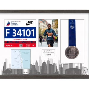 May include: A dark wood-framed display case featuring a Chicago Marathon race bib with the number F 34101, a photograph of a runner, a blue medal with a ribbon, a map of the course, and a plaque reading Joseph Moore October 11th 2026 5:24:06.