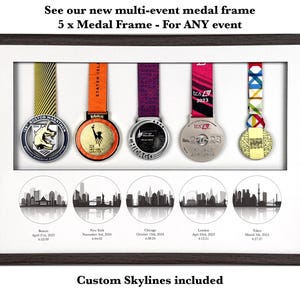May include: A dark wood rectangular shadow box frame containing five hanging marathon medals with colorful ribbons. Below the medals are five circular black and white city skyline illustrations labeled Boston, New York, Chicago, London, and Tokyo.