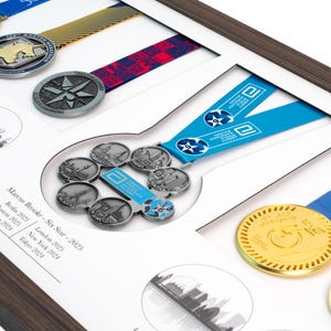 May include: A wooden display frame containing multiple marathon medals with colorful ribbons. The center features a Six Star medal with a blue ribbon. Text on the white mat board reads: Marcus Brooke - Six Star - 2025, Berlin 2025, Boston 2025, Chicago 2024, London 2025, New York 2024, Tokyo 2024.