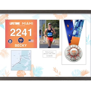 May include: Framed display featuring a marathon bib, a photo of a runner, a race map, and a medal. The bib reads "LIFE TIME MIAMI MARATHON" with the number 2241 and the name "BECKY". The medal has a palm tree design.