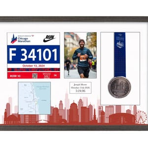 May include: A framed Chicago Marathon display featuring a race bib with the number F 34101, a photograph of a runner, a finisher medal on a blue ribbon, a course map, and a plaque with the text Joseph Moore, October 11th 2026, 5:24:06.