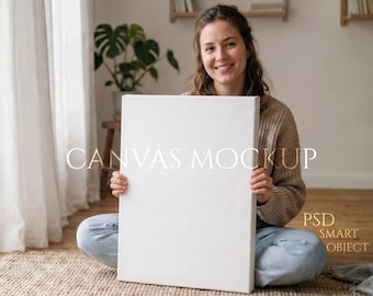 Könnte beinhalten: Eine Person sitzt im Schneidersitz und hält eine leere, weiße Leinwand. Die Leinwand ist rechteckig und auf einen Holzrahmen gespannt. Auf der Leinwand steht "CANVAS MOCKUP" und "PSD SMART OBJECT". Der Hintergrund umfasst ein Fenster, eine Pflanze und einen Teppich.