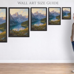 Puede incluir: Gu&iacute;a de tama&ntilde;os de arte mural con pinturas de paisajes enmarcadas. Las pinturas representan una escena de lago de monta&ntilde;a con un lago azul, &aacute;rboles verdes y monta&ntilde;as. El texto "WALL ART SIZE GUIDE" est&aacute; en la parte superior. Una mujer est&aacute; al lado del arte.