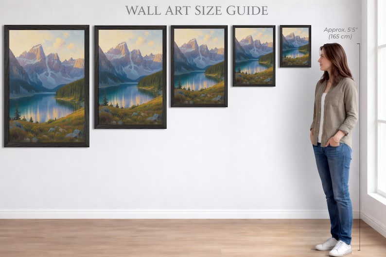 Puede incluir: Gu&iacute;a de tama&ntilde;os de arte mural con pinturas de paisajes enmarcadas. Las pinturas representan una escena de lago de monta&ntilde;a con un lago azul, &aacute;rboles verdes y monta&ntilde;as. El texto "WALL ART SIZE GUIDE" est&aacute; en la parte superior. Una mujer est&aacute; al lado del arte.