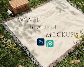 Könnte beinhalten: Ein Mockup für eine gewebte Decke mit dem Text „WOVEN BLANKET MOCKUP“ auf Gras. Ein Picknickkorb und eine Weinflasche sind in der Nähe der Decke platziert. Die Decke hat einen Fransenrand.