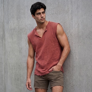 May include: A sleeveless, brick-red top with a V-neck and distressed edges. Paired with brown shorts with frayed hems. The outfit is casual and relaxed, suitable for warm weather.