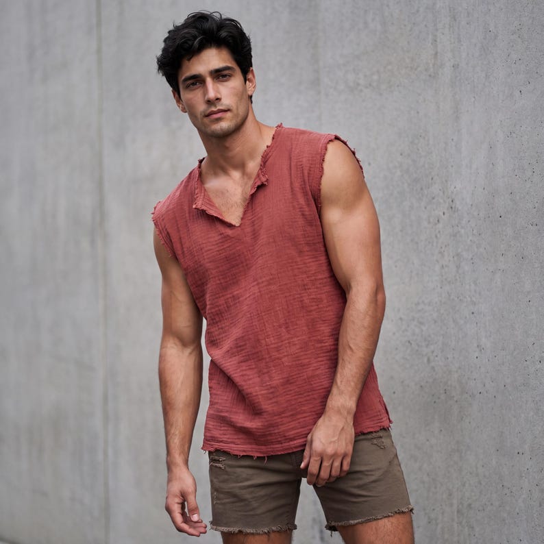 May include: A sleeveless, brick-red top with a V-neck and distressed edges. The top is paired with olive-green shorts with frayed hems. The outfit is casual and suitable for warm weather.