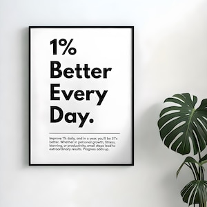 以下が含まれることがあります： 太字の黒いフォントで「1% Better Every Day」というテキストが書かれた黒いフレームのウォールアート。このアートワークには、毎日の改善に関するモチベーションメッセージが含まれています。大きな緑の葉を持つ鉢植えの植物が背景にあります。
