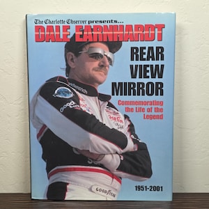 Könnte beinhalten: Ein Buchcover mit Dale Earnhardt und dem Titel "Rear View Mirror". Das Cover hat einen hellblauen Hintergrund mit dem Text "The Charlotte Observer presents..." und "Commemorating the Life of the Legend."