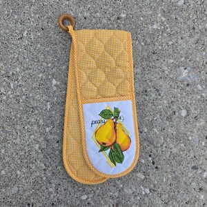 May include: A yellow and white checkered quilted oven mitt featuring a white rectangular patch with a graphic of two yellow pears on a green stem with leaves. The word pears is printed in black script text above the fruit illustration.