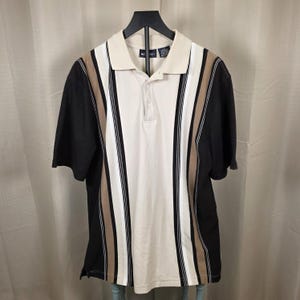 May include: A polo shirt with a cream-coloured collar and a vertical striped design. The shirt features alternating stripes of black, tan, white, and cream. The short-sleeved shirt is hanging on a black hanger.