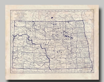 May include: A vintage map of North Dakota, printed in blue ink on a cream-colored background. The map shows the state's counties and major cities, with a grid of longitude and latitude lines.