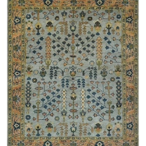 May include: Rectangular area rug with a light blue central field and an intricate floral pattern in shades of navy, peach, and cream. The border is a warm peach color with geometric designs. The rug has a fringed edge.