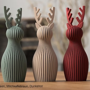 Pu&ograve; includere: Tre statuette di renne stilizzate con un design a coste verticali. La figura a sinistra &egrave; verde tenue, quella centrale &egrave; beige e quella a destra &egrave; rosso scuro. Ogni renna presenta palchi prominenti e una forma del corpo liscia e arrotondata.