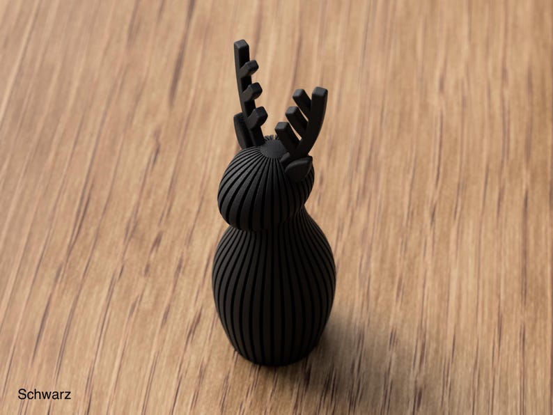 Pu&ograve; includere: Una statuetta nero opaco a forma di cervo con una texture a coste verticali che copre il corpo arrotondato, la testa e le corna. L'oggetto presenta una base solida e liscia con una finitura scura uniforme su tutta la sua struttura.