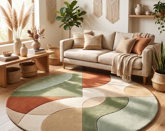 Puede incluir: Una alfombra circular grande con un patrón geométrico de líneas curvas y rectas en tonos suaves de verde salvia, naranja terracota, beige y crema. La alfombra tiene una textura suave y está colocada sobre un suelo de madera clara.