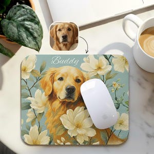 Puede incluir: Alfombrilla de ratón personalizada con una ilustración de Golden Retriever rodeada de flores blancas sobre un fondo azul claro. El nombre "Buddy" está escrito en la parte superior. Un ratón blanco descansa sobre ella.
