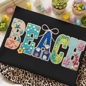 Puede incluir: Una superficie negra muestra la palabra "BEACH" en letras de ganchillo coloridas. Cada letra está adornada con elementos temáticos de playa como estrellas de mar, conchas marinas y coral. Las letras están delineadas con un borde perlado.