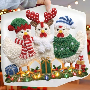 May include: A festive cushion featuring three white chickens in Christmas outfits. One chicken wears a green elf hat and a red and white scarf, another a reindeer antler headband, and the third a blue and white striped hat and green sweater.