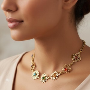 May include: Gold-toned necklace featuring intricate floral and starburst designs. The necklace is adorned with colorful gemstones in shades of red, green, blue, and yellow. The necklace is worn around the neck.