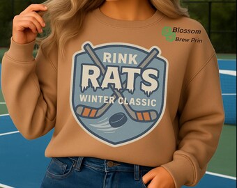 May include: A tan sweatshirt featuring a blue and white hockey-themed graphic that reads "Rink Rats Winter Classic." The graphic includes hockey sticks and a puck. The text "PNG File - Digital Download Only (No Physical Item)" is at the bottom.