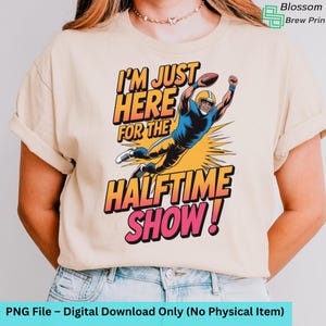 Op de afbeelding: Beige t-shirt met de tekst "I'M JUST HERE FOR THE HALFTIME SHOW!" en een afbeelding van een American footballspeler. Het ontwerp gebruikt oranje, geel, blauw en roze. Het is een digitale download.