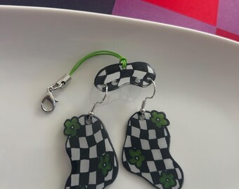 Pendientes de cuadros negros con flores verdes y dos pares de soportes para pendientes.