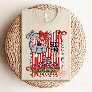 May include: A cream-coloured t-shirt with a graphic of a bulldog wearing red sunglasses. The design includes the words "BULLDOGS", "SIC 'EM", and "Go Dawgs", set against red and white stripes.