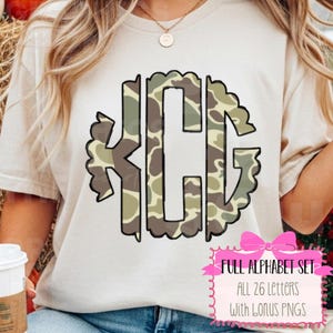 May include: A beige t-shirt featuring a monogram design with the letters KCG in a camouflage pattern. The letters are outlined in black with a scalloped edge. A pink bow graphic with text that reads "FULL ALPHABET SET ALL 26 LETTERS With BONUS PNGS" is in the lower right corner.