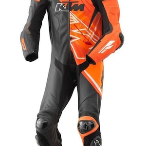 Op de afbeelding: Zwart en oranje motorracepak met het KTM-logo. Het pak heeft een combinatie van zwarte en oranje panelen, met witte accenten. Het heeft beschermende padding op de knieën en ellebogen en is ontworpen voor veiligheid en prestaties.