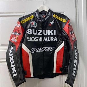 May include: Black leather motorcycle jacket with red and white accents. The jacket features the Suzuki and Yoshimura logos, along with Dunlop and Rocket branding. The jacket is hanging on a white hanger.
