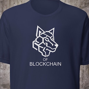Puede incluir: Camiseta azul marino con un diseño de cabeza de lobo geométrico blanco. El texto "OF BLOCKCHAIN" está impreso debajo del gráfico. La camiseta está hecha de un material suave y tiene cuello redondo.