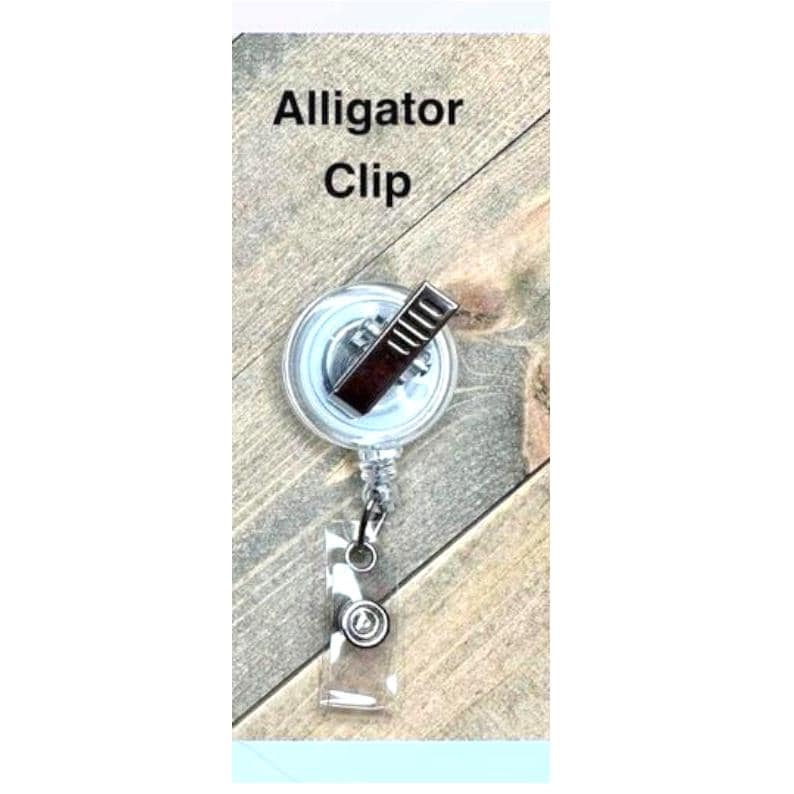 Op de afbeelding: Een doorzichtige, oprolbare badgehouder met een alligatorclip. De haspel heeft een zilverkleurige metalen clip en een transparante plastic band met een druksluiting. De tekst "Alligator Clip" is zwart gedrukt.