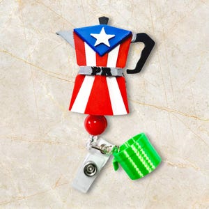 May include: A badge reel featuring a coffee pot design in the colors of the Puerto Rican flag: red and white stripes, a blue triangle with a white star. Includes a green cup and a red bead.