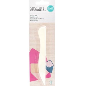 May include: A white plastic bone folder scoring tool packaged on a branded card labeled Crafter's Essentials. The packaging features text in multiple languages including Scoring Tool, Outil D'entaille, Herramienta Para Marcar, and Kerbwerkzeug.