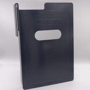 Puede incluir: Un organizador Sidekick gris oscuro con asa y un recorte rectangular. El logotipo de Sidekick es visible en la parte delantera. La parte inferior del organizador tiene el texto: [www.sidekicksupplies.com].