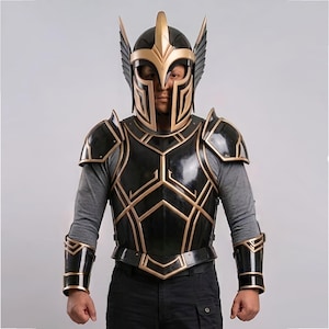 Puede incluir: Un conjunto de armadura de guerrero negro y dorado. El casco presenta una cresta dorada y detalles en forma de alas. La armadura del pecho y los hombros tiene diseños geométricos dorados. El conjunto incluye protectores de brazos y una placa para el pecho, todo con un acabado brillante.