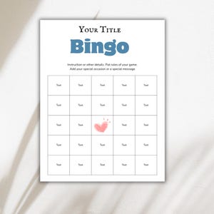 May include: A printable Bingo game template on white paper. The title "Bingo" is in blue, with space for a custom title above. The grid has 25 blank squares for text, with a pink heart graphic in the center.
