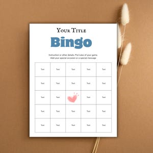 May include: A white Bingo game card with the title "YOUR TITLE" and the word "Bingo" in blue. The card includes instructions and a grid of boxes labeled "Text", with a pink heart graphic. Dried flowers are in the background.