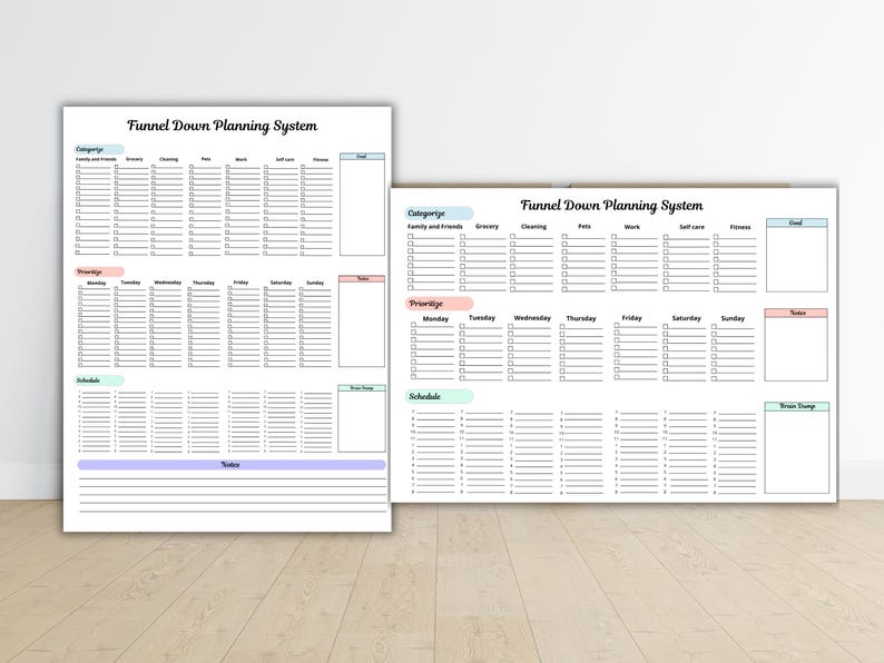 May include: Two white sheets of paper with the text "Funnel Down Planning System" are displayed. The sheets are divided into sections for categories, priorities, schedule, and notes. The sheets are on a light brown surface.