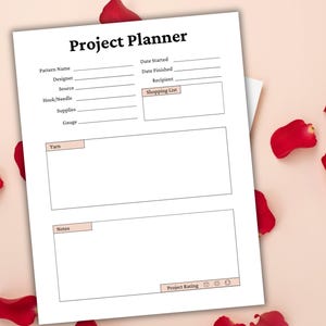 May include: A white Project Planner sheet with sections for pattern details, shopping list, yarn, notes, and project rating. The title "Project Planner" is at the top. Red rose petals are scattered around the planner on a pink background.