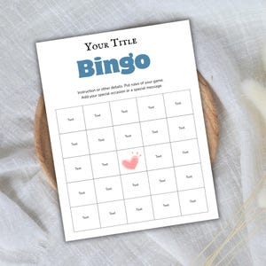 May include: A white Bingo game card with the title "Your Title" and the word "Bingo" in blue. The card has a grid of boxes labeled "Text" and a pink heart illustration. Instructions are included.